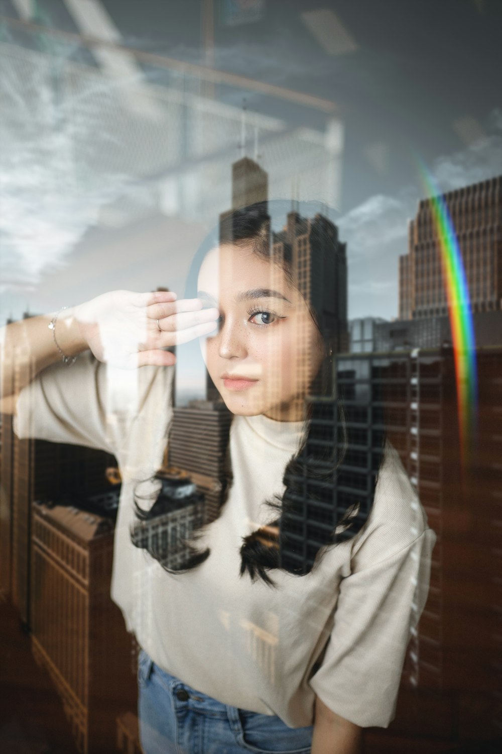 a woman standing in front of a window with a rainbow in the background