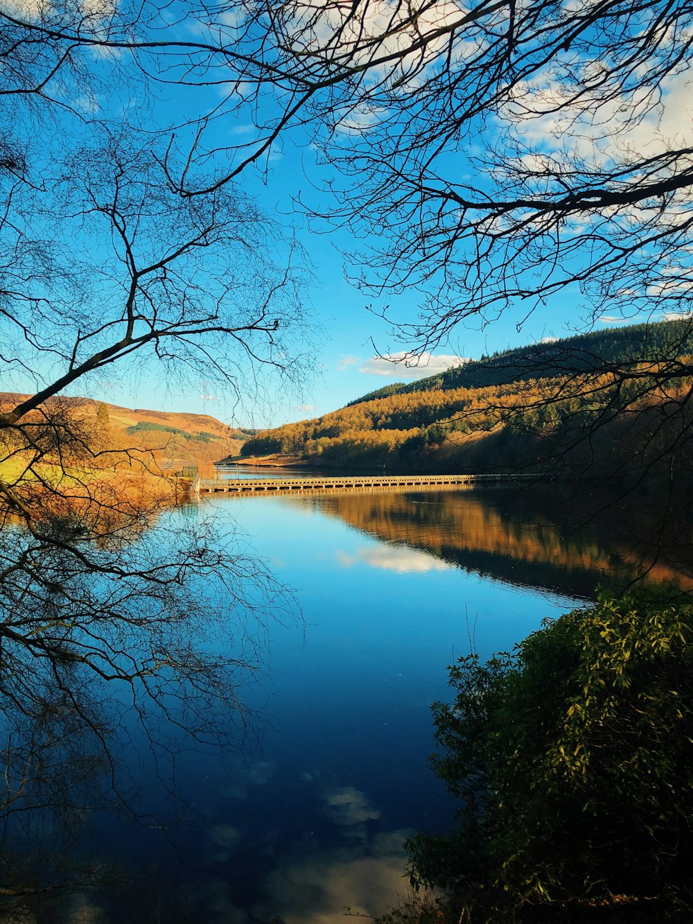 a body of water surrounded by trees and hills