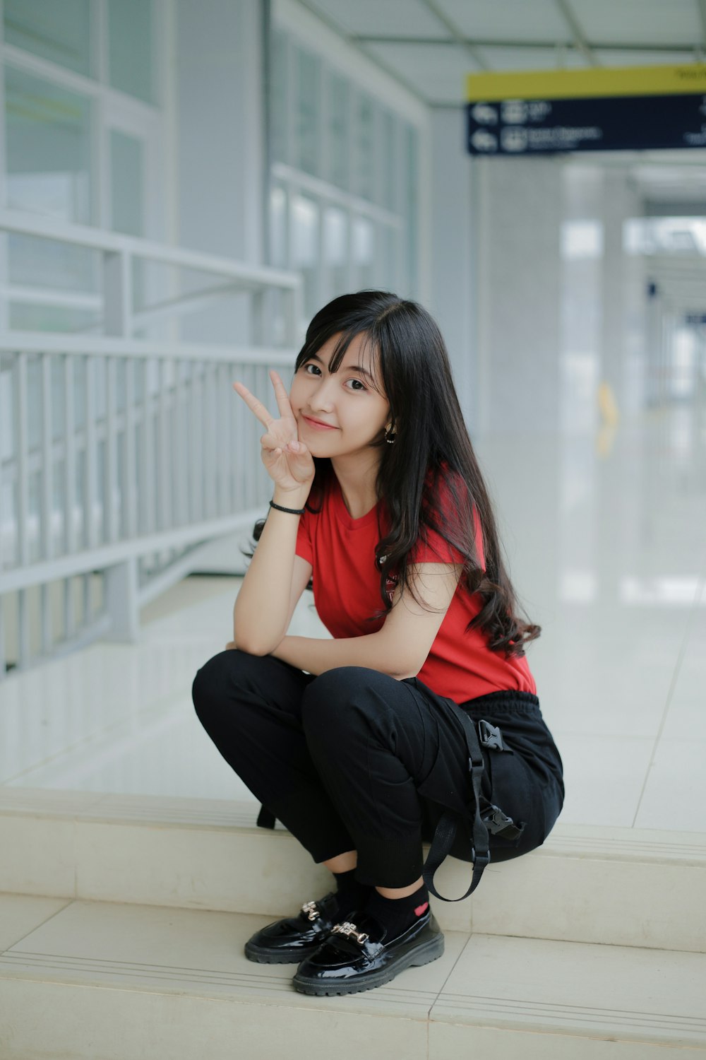 a woman sitting on a step making a peace sign