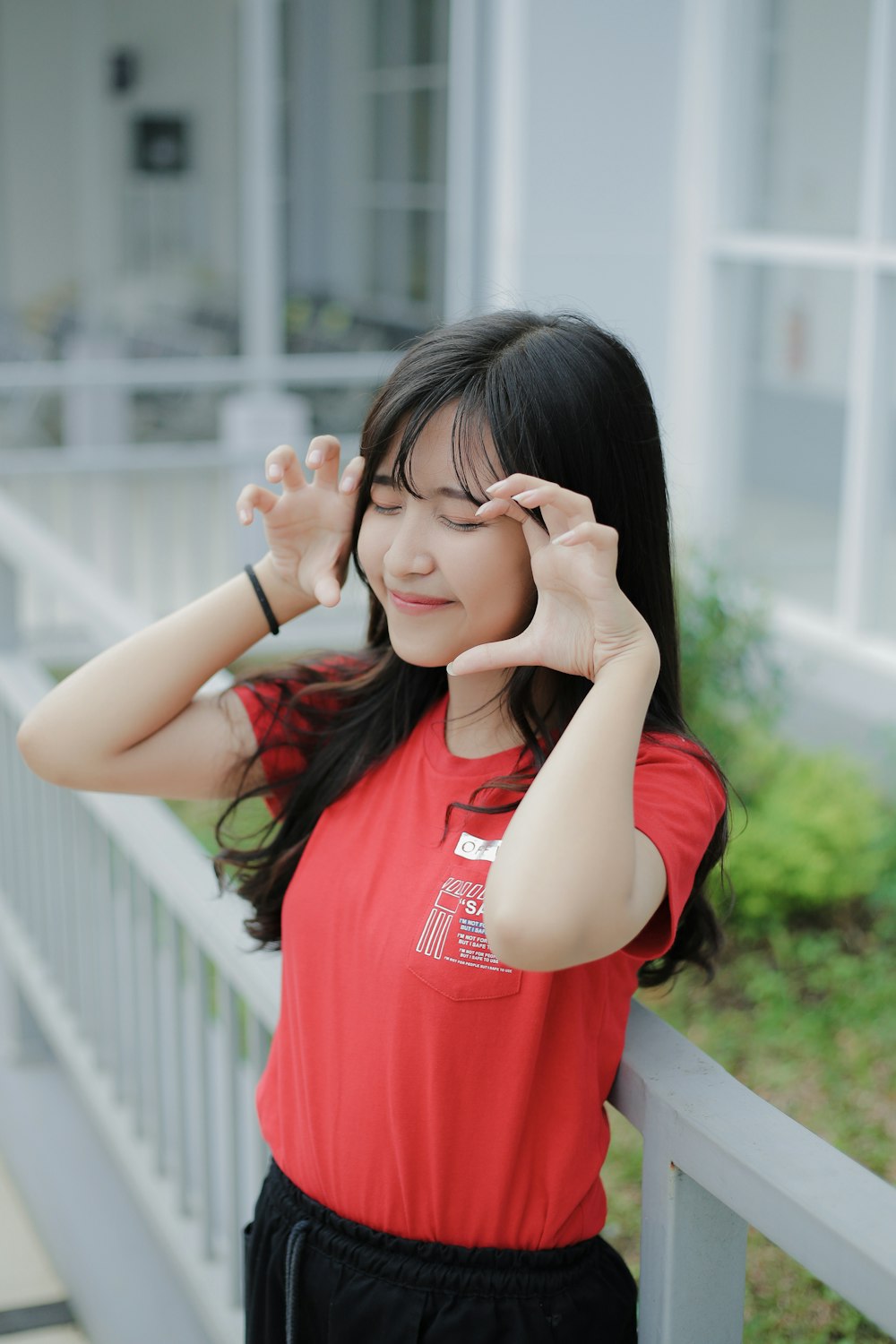 a woman in a red shirt leaning on a rail