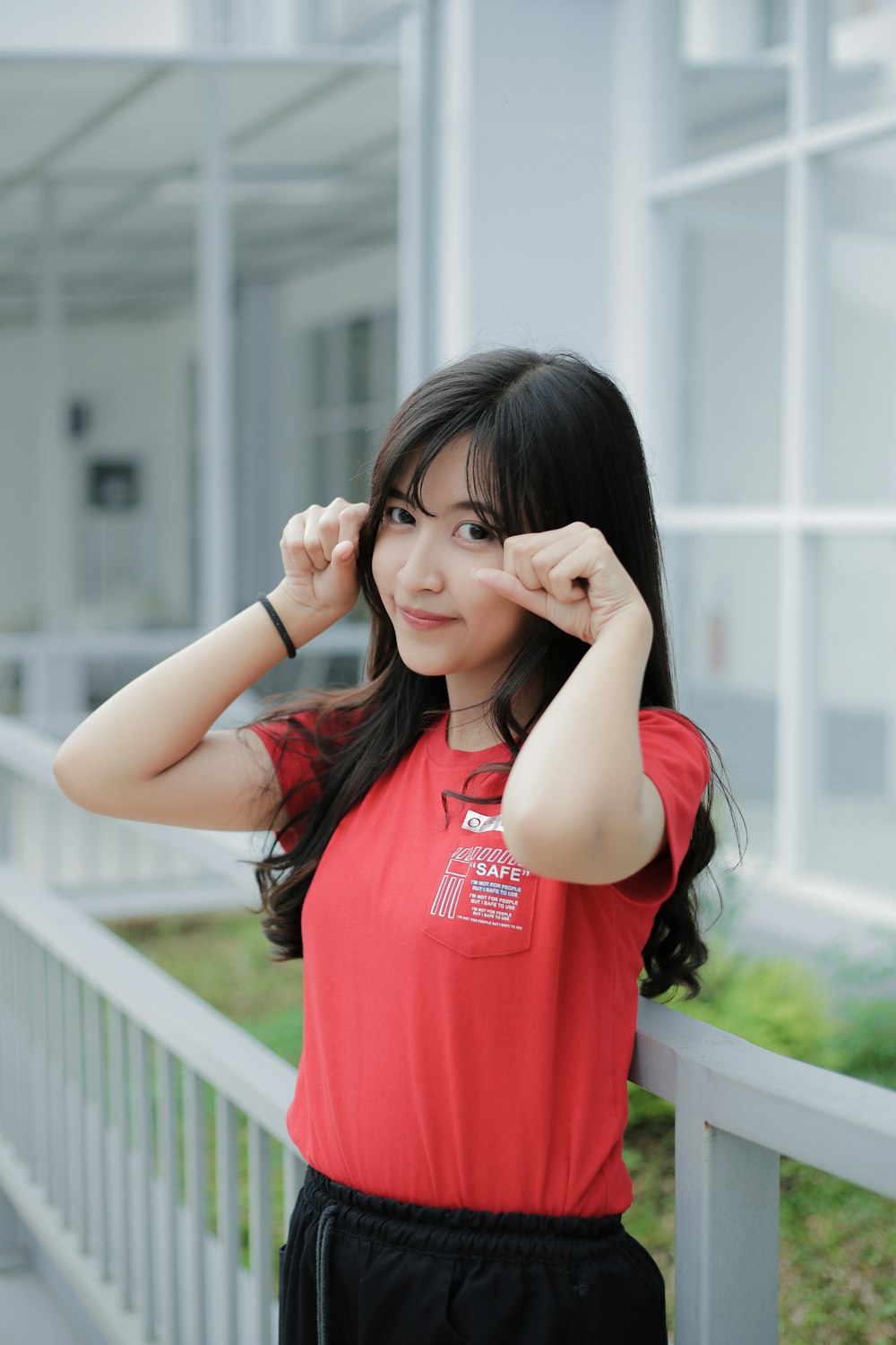 a woman in a red shirt leaning on a rail