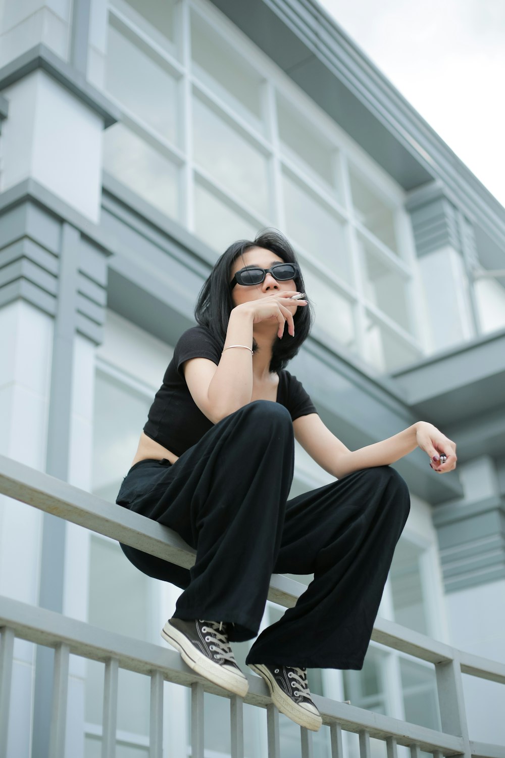 a woman sitting on top of a metal rail next to a building