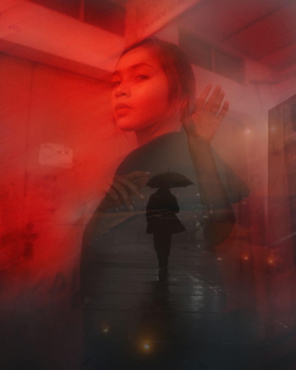a woman holding an umbrella standing in front of a red light