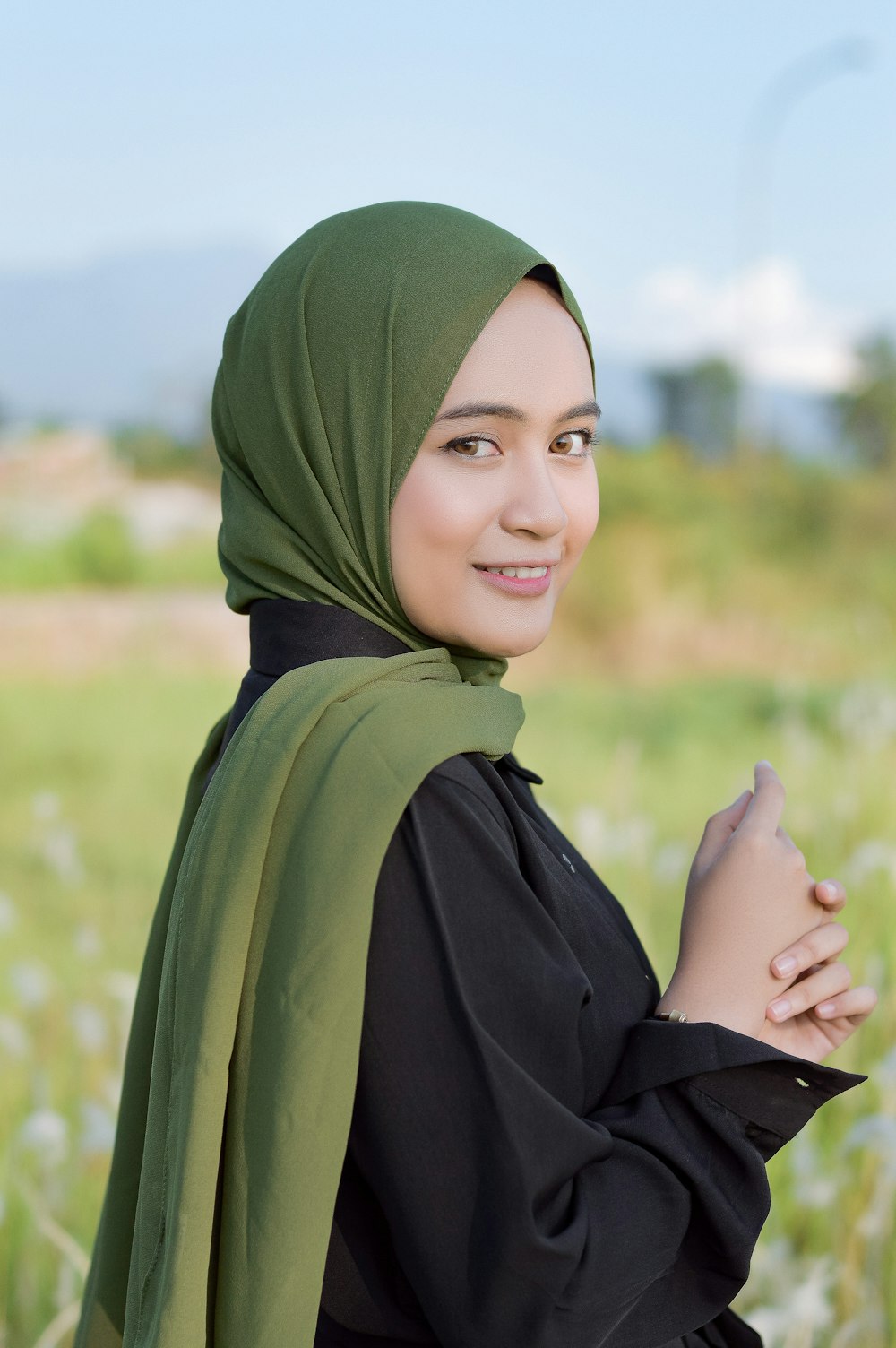 a woman in a hijab standing in a field