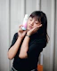 Portrait of a smiling woman with glowing skin holding a bottle of castor oil.