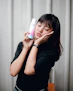 A happy young woman with glowing skin holding a Cantikara skincare product with a pastel pink background.