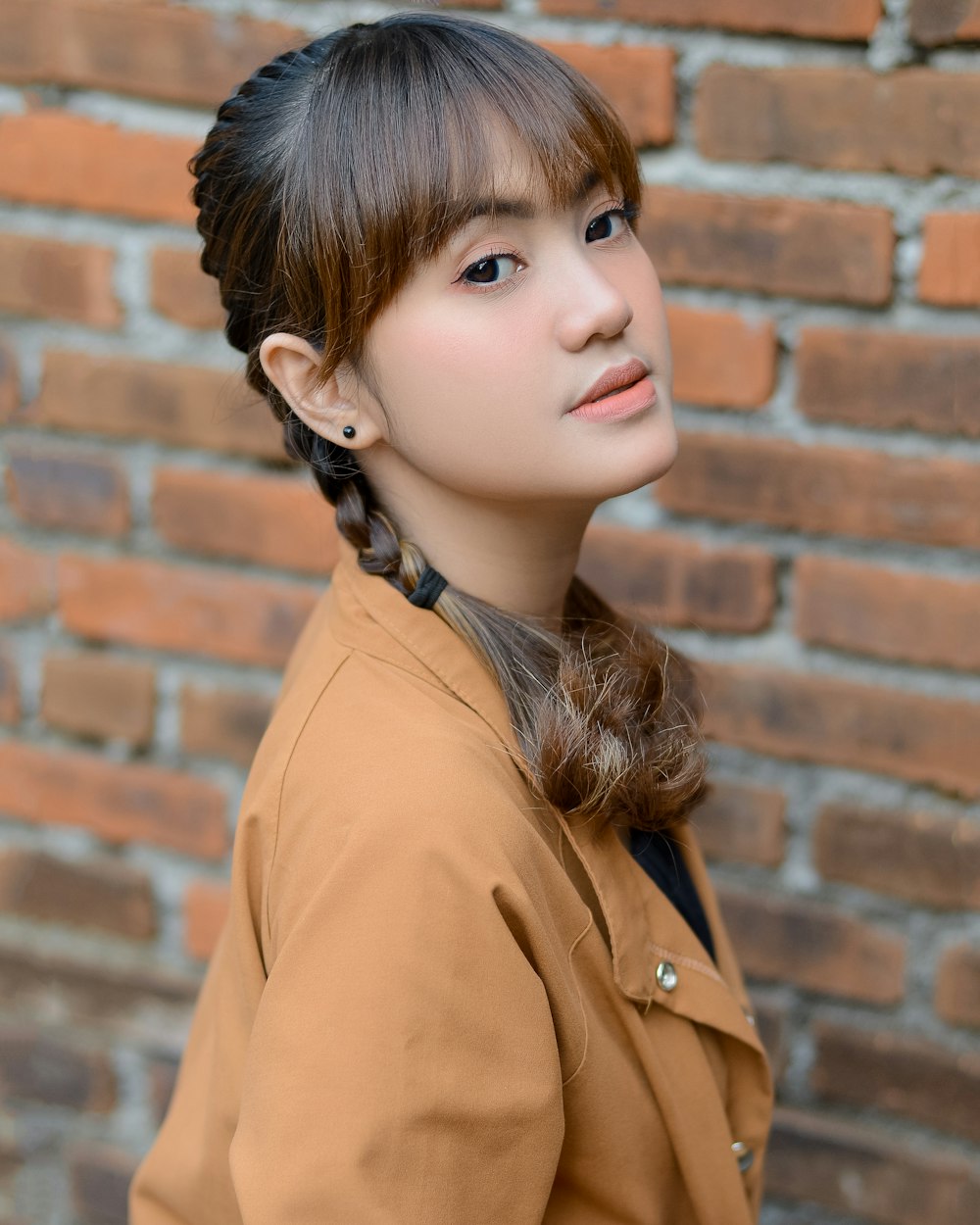 a woman standing in front of a brick wall