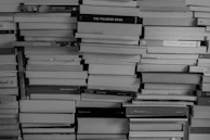 Artistic black and white photo of stacked ebooks with thin sans-serif titles.