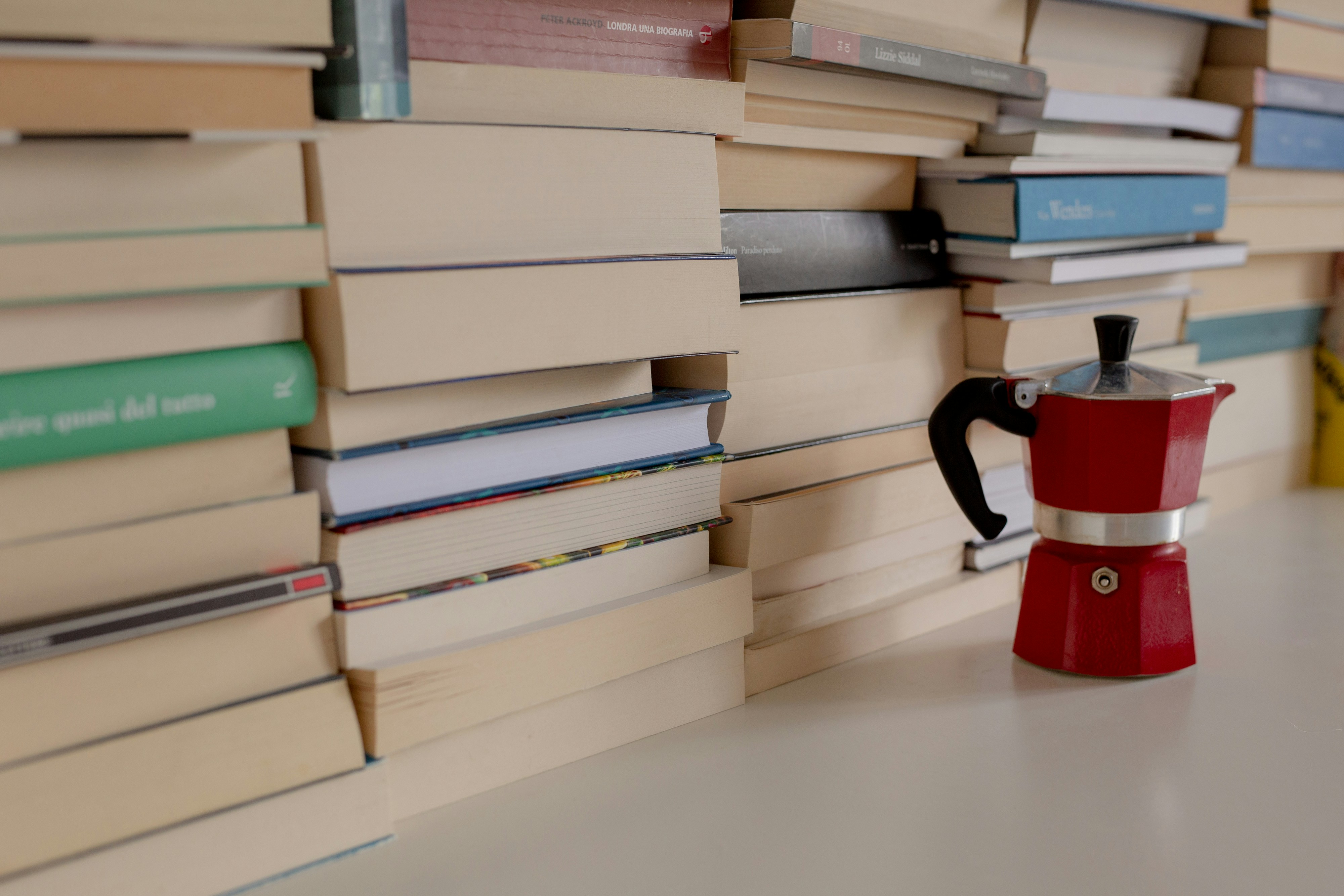 a stack of books next to a red coffee pot