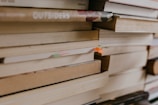 Close-up of a stack of well-loved books with a warm reading nook in the background.