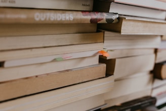 A stack of colorful novels with a cozy reading nook in the background.