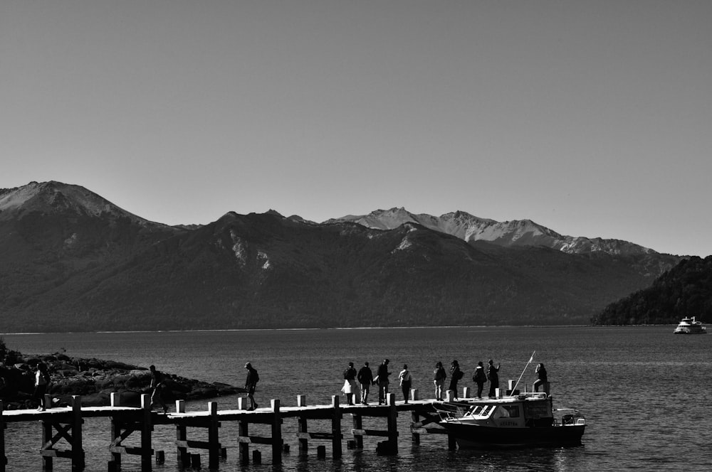 a group of people standing on a pier next to a body of water