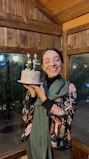 Happy person holding a freshly baked cake with a big smile in a cozy kitchen