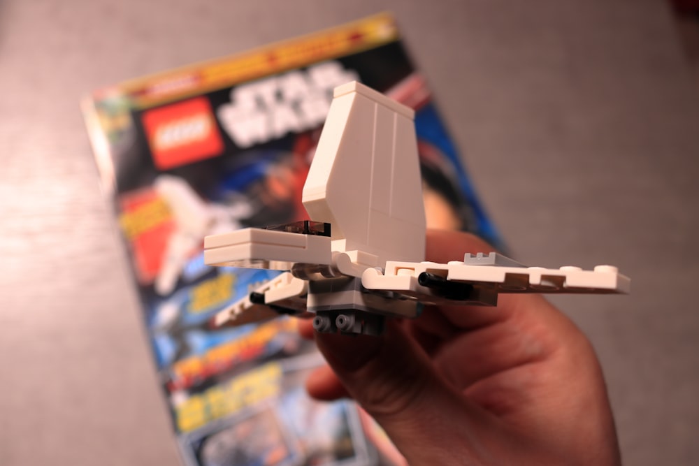 a hand holding a lego star wars fighter jet
