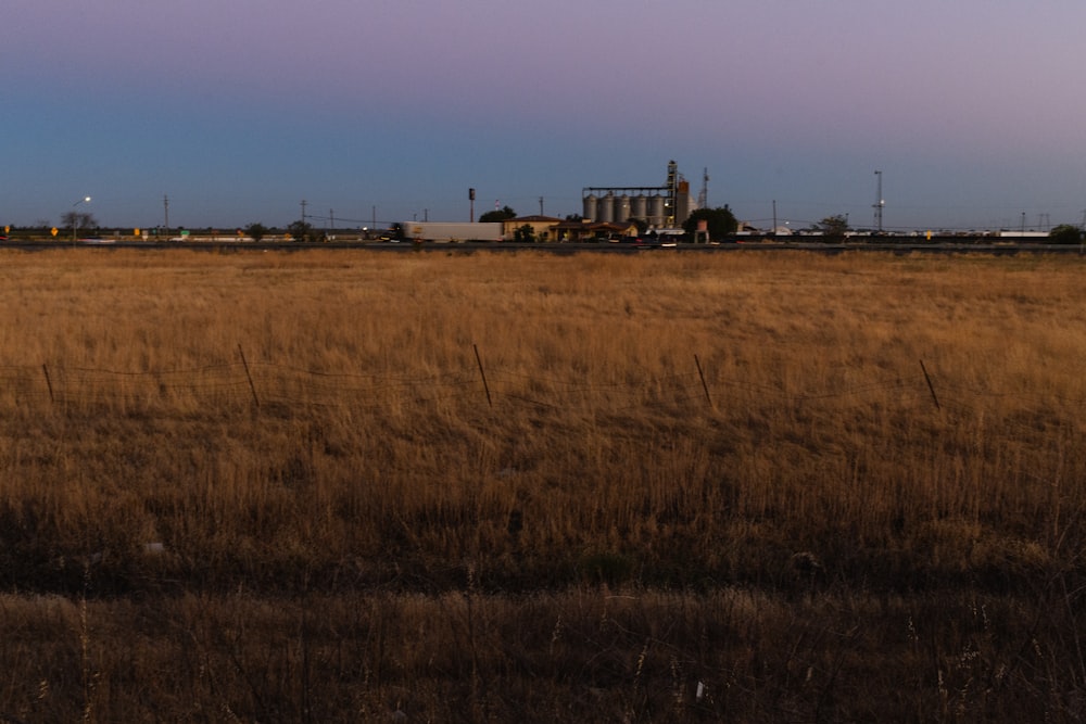 a large field with a factory in the distance