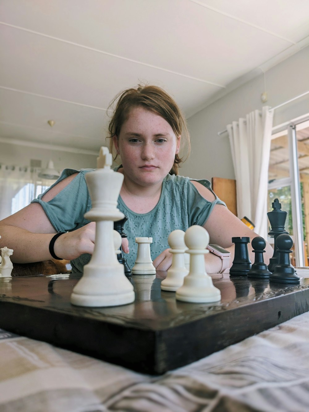 a woman sitting at a table with a chess set