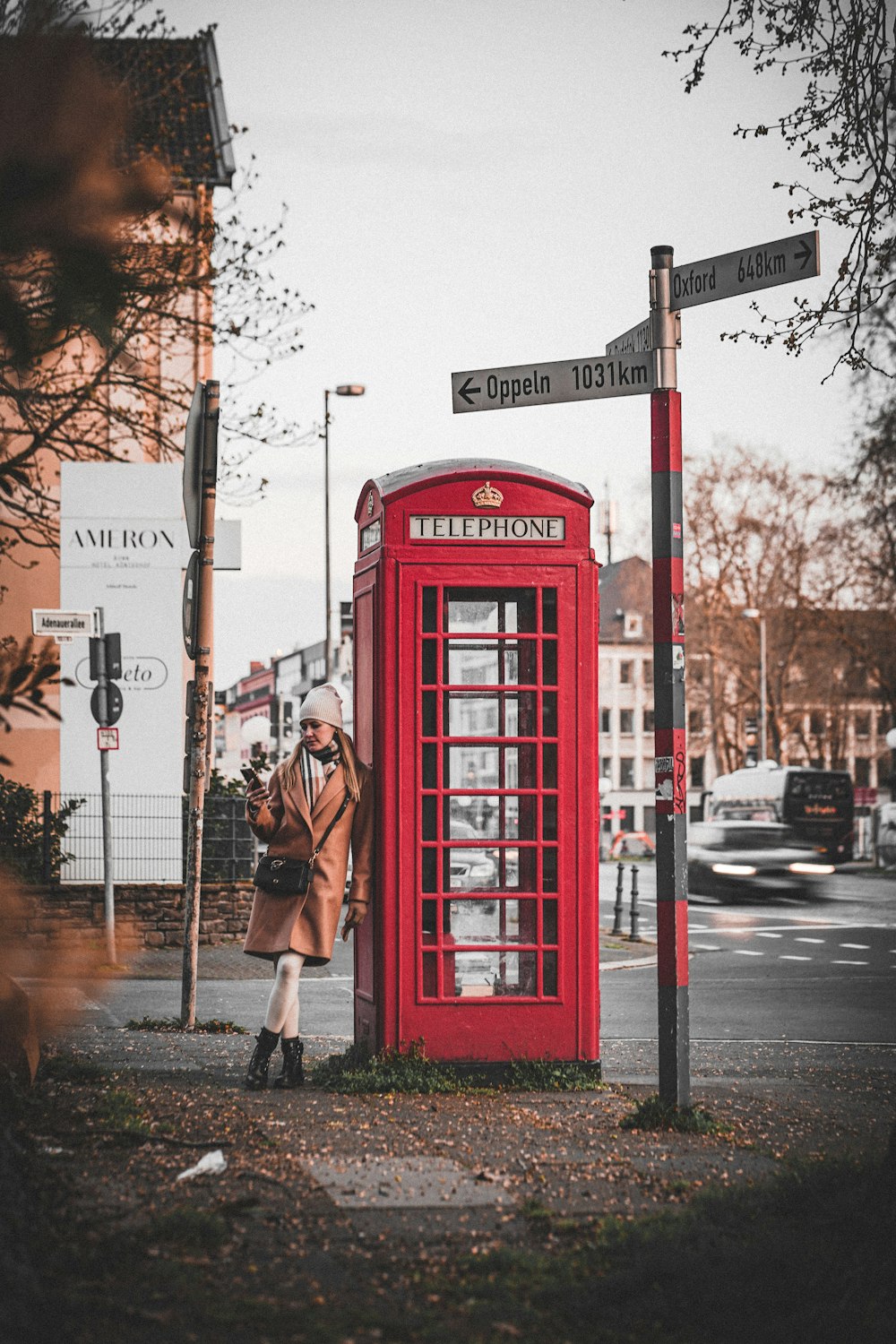 a woman standing next to a red phone booth
