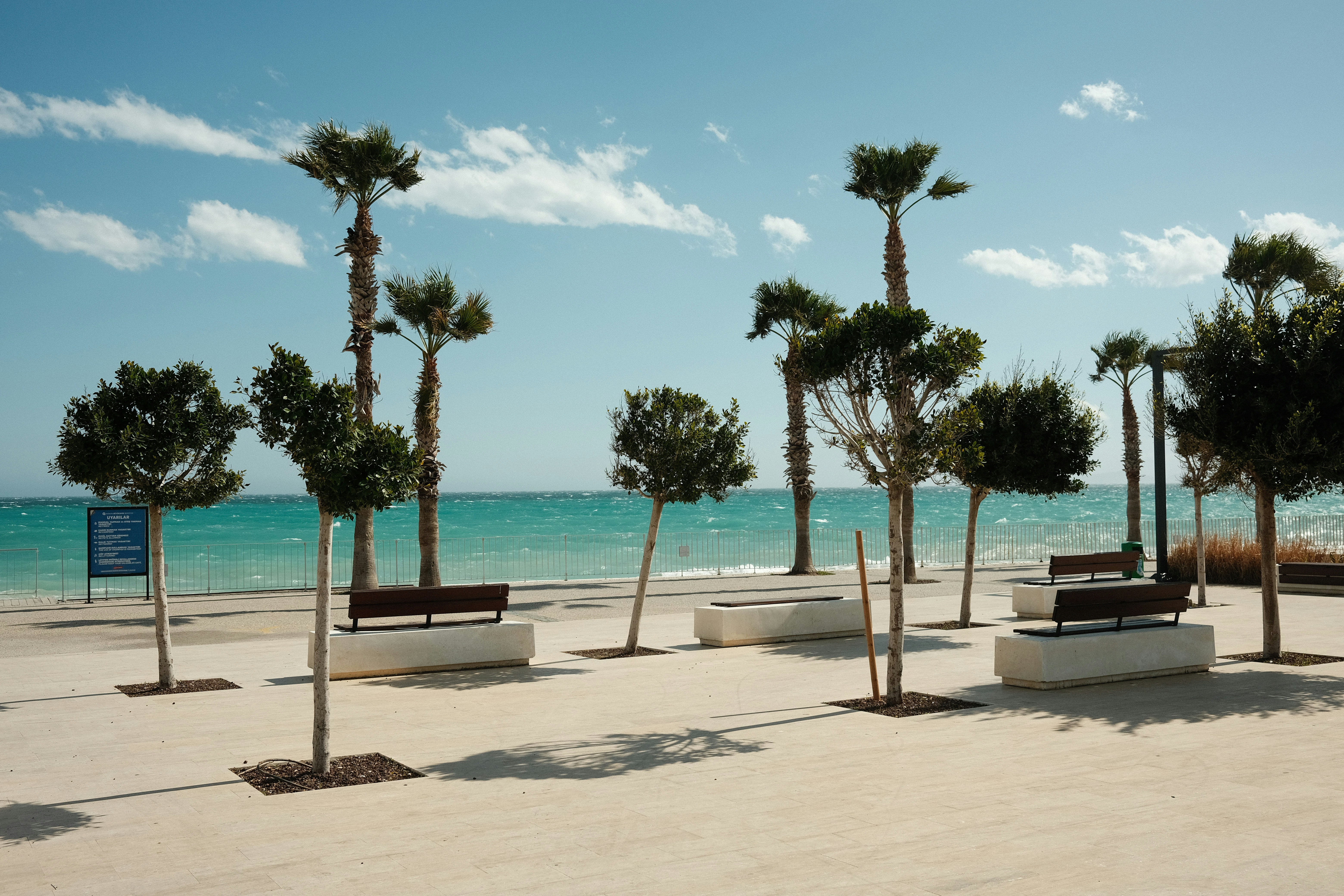 a row of benches sitting on top of a sandy beach, View at Konyaaltı Beach in Antalya.