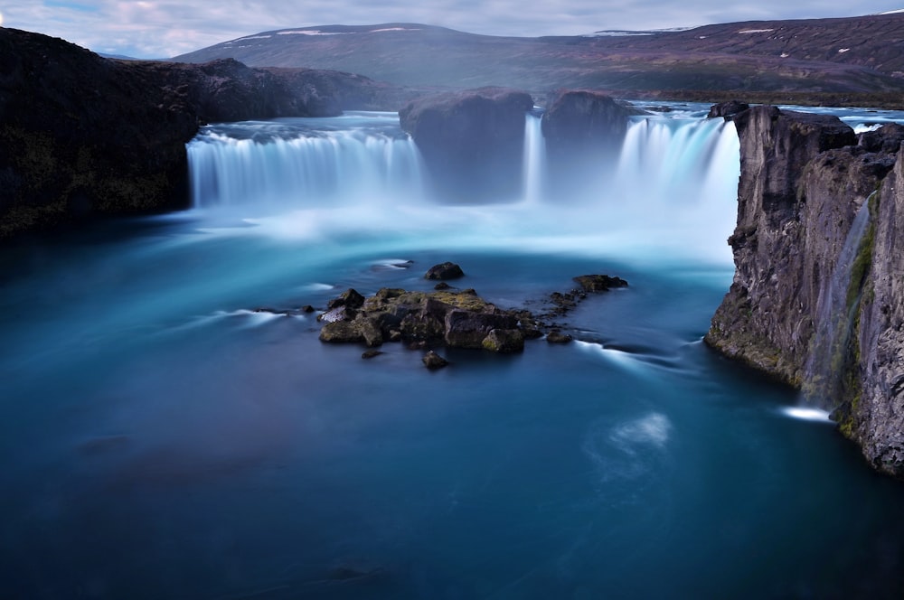 a large waterfall with blue water surrounded by mountains