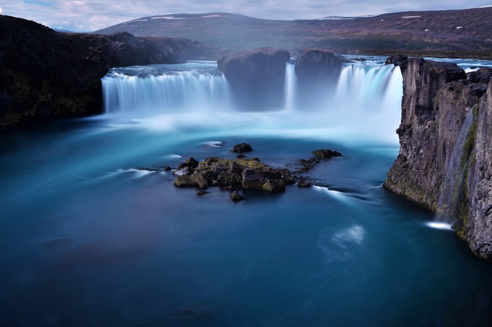 Una grande cascata con acqua blu circondata da montagne