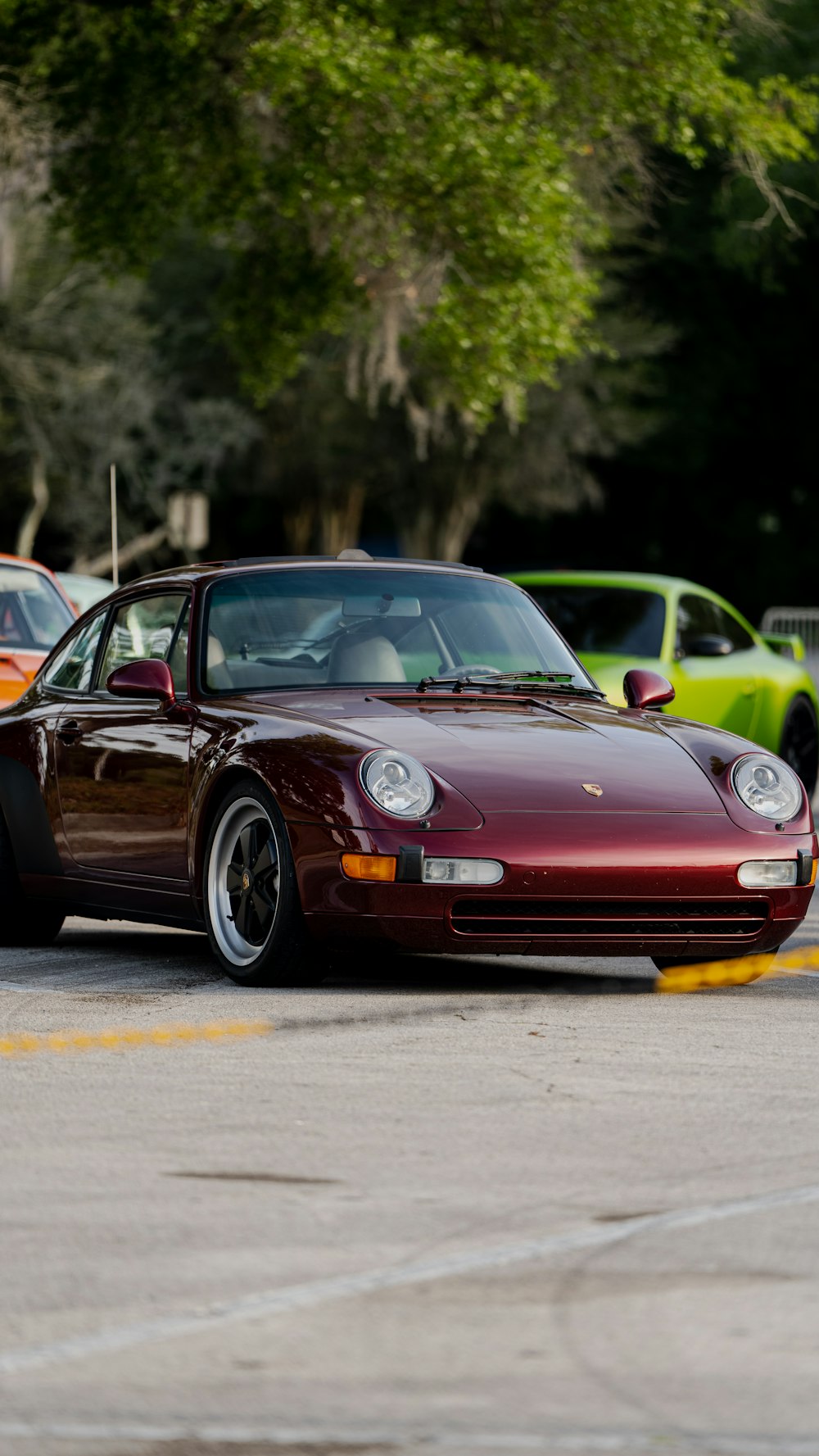 a maroon sports car parked in a parking lot