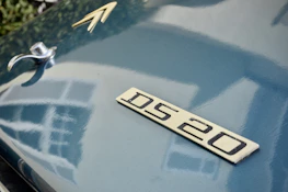 Close-up of a beautifully restored 2CV hood ornament shining in daylight.