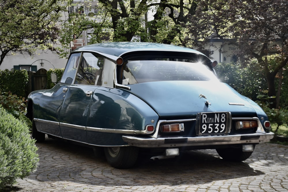 a blue car parked on a cobblestone street