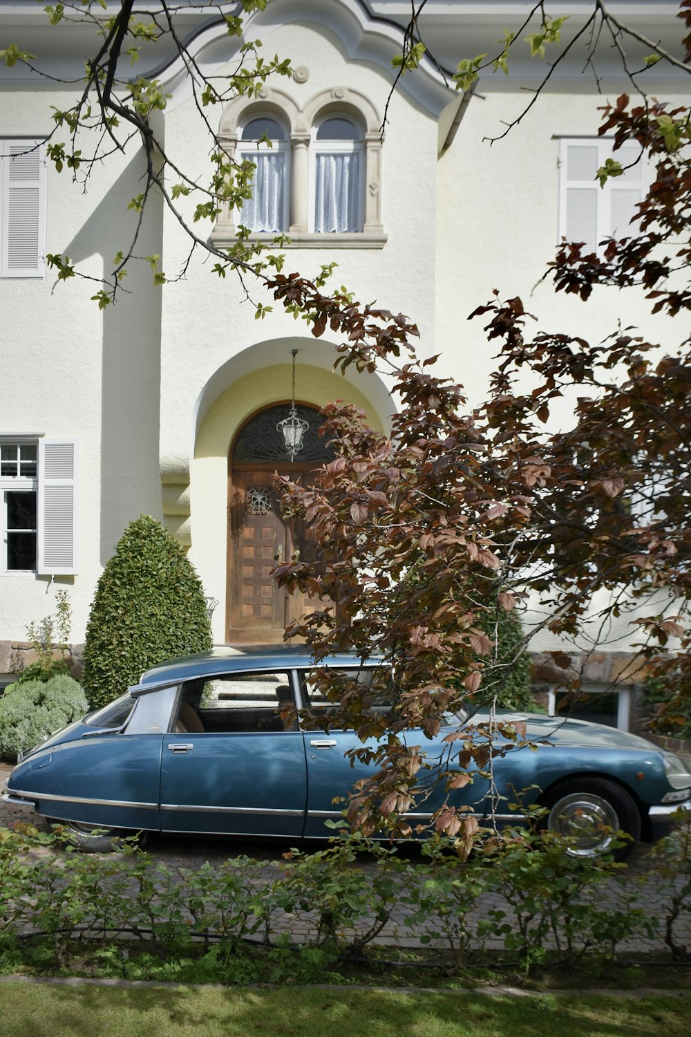 a blue car parked in front of a white house