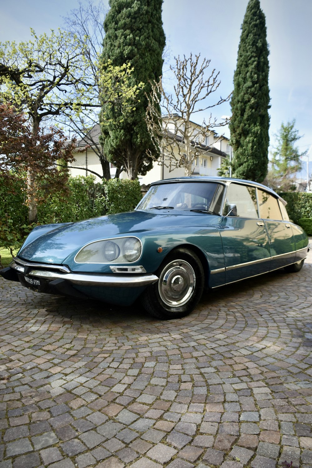 a blue car is parked on a cobblestone driveway