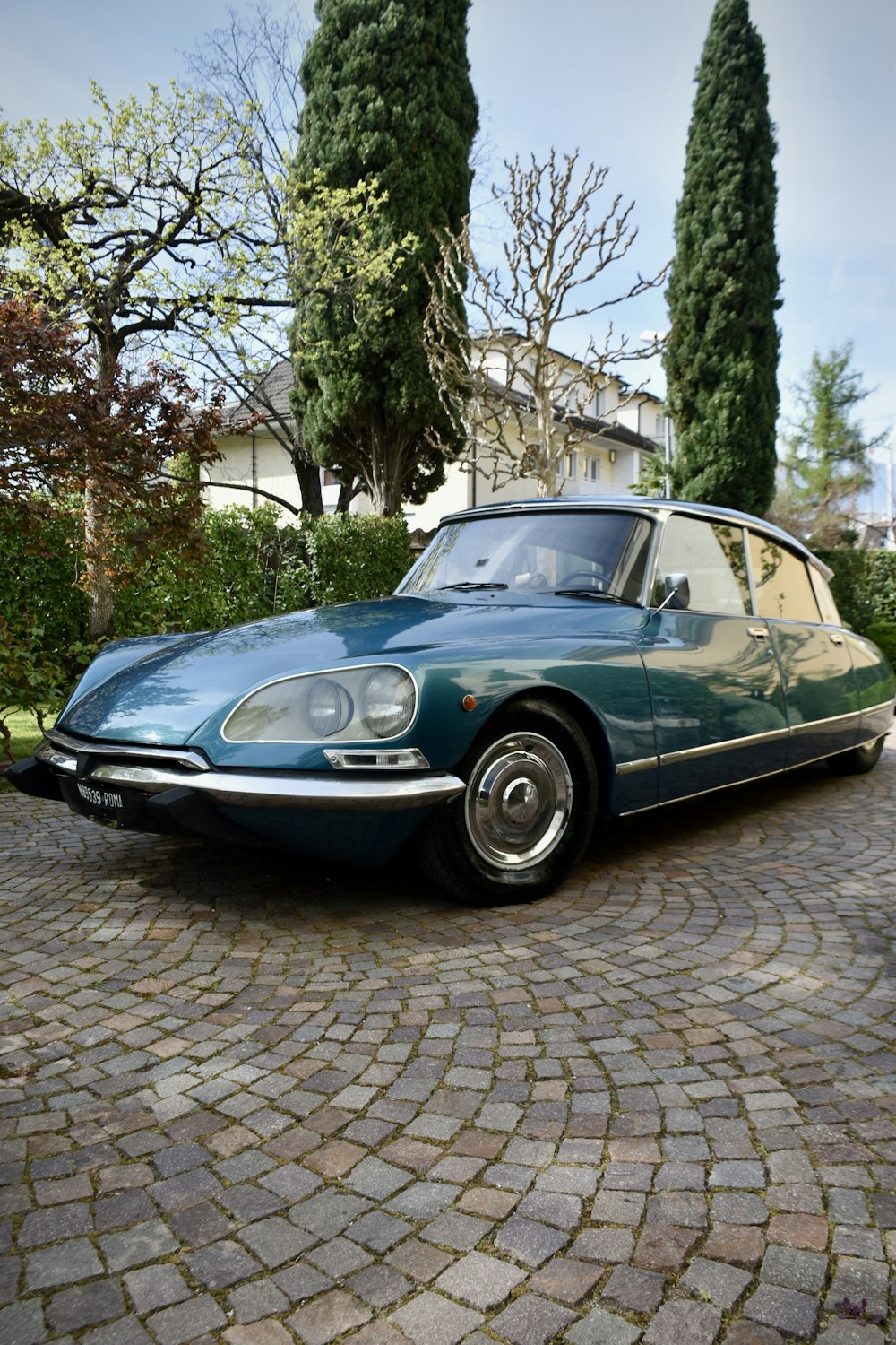 a blue sports car parked on a cobblestone driveway