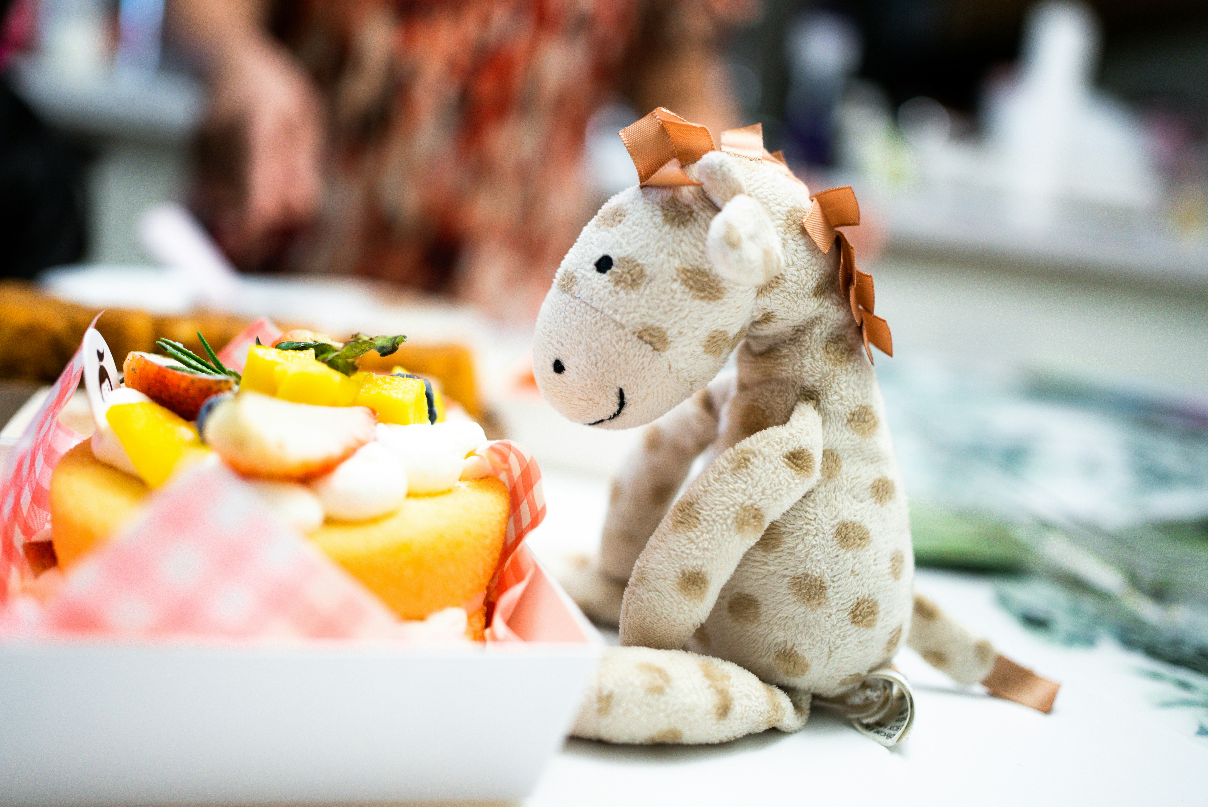 a stuffed giraffe sitting next to a plate of fruit