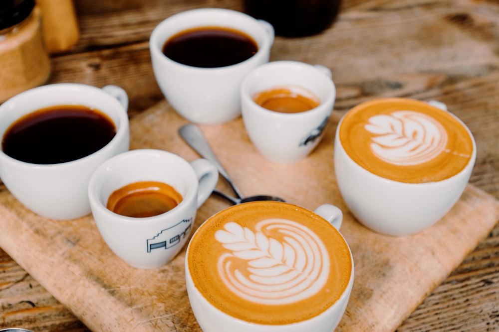 a wooden tray topped with four cups of coffee