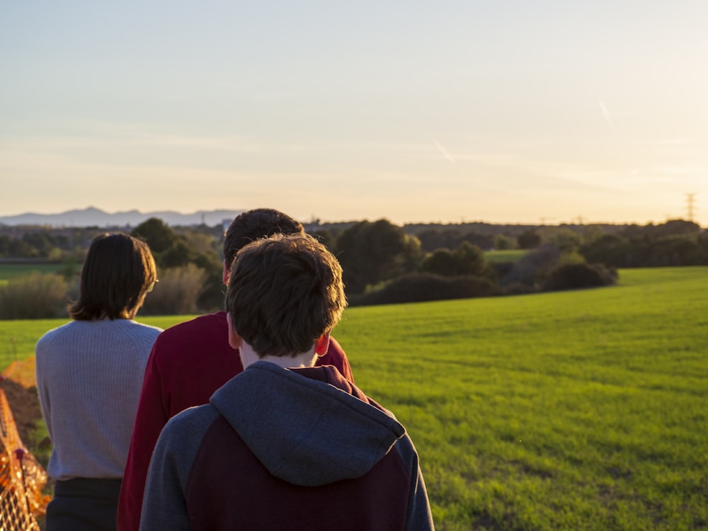 a group of people walking across a lush green field