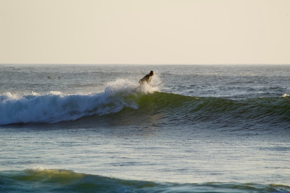 una persona montando una ola encima de una tabla de surf