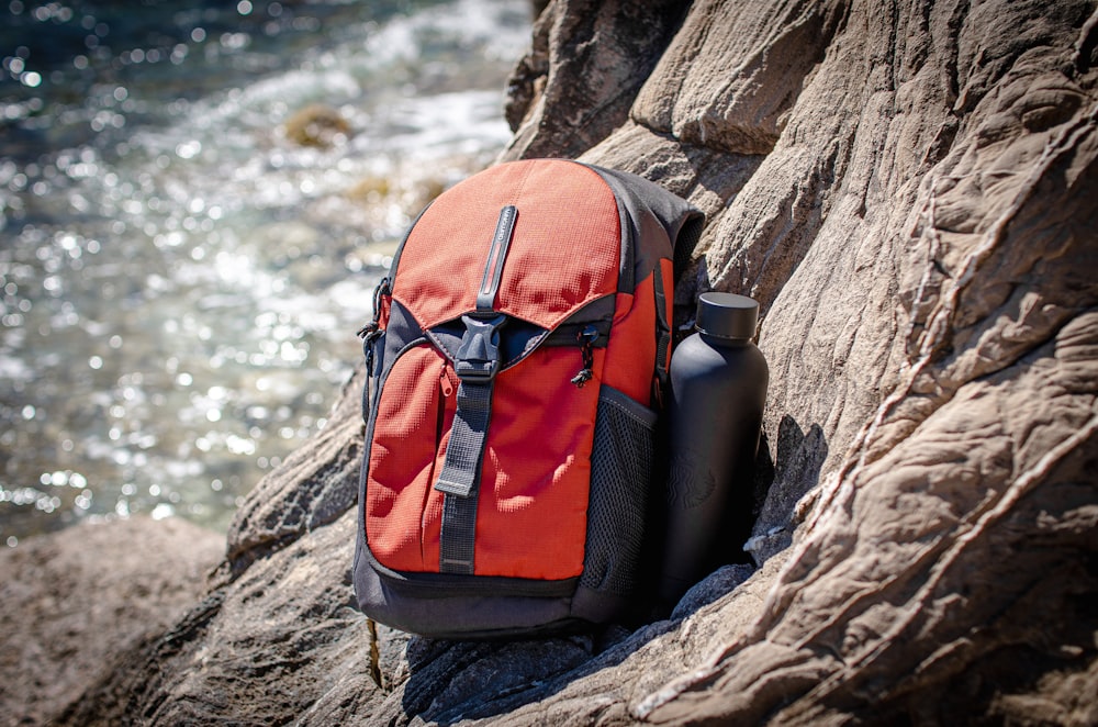 a backpack sitting on top of a rock next to a body of water