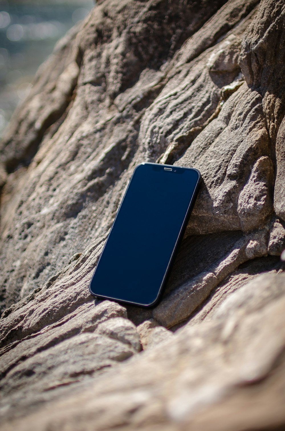 a cell phone laying on a rock by the water