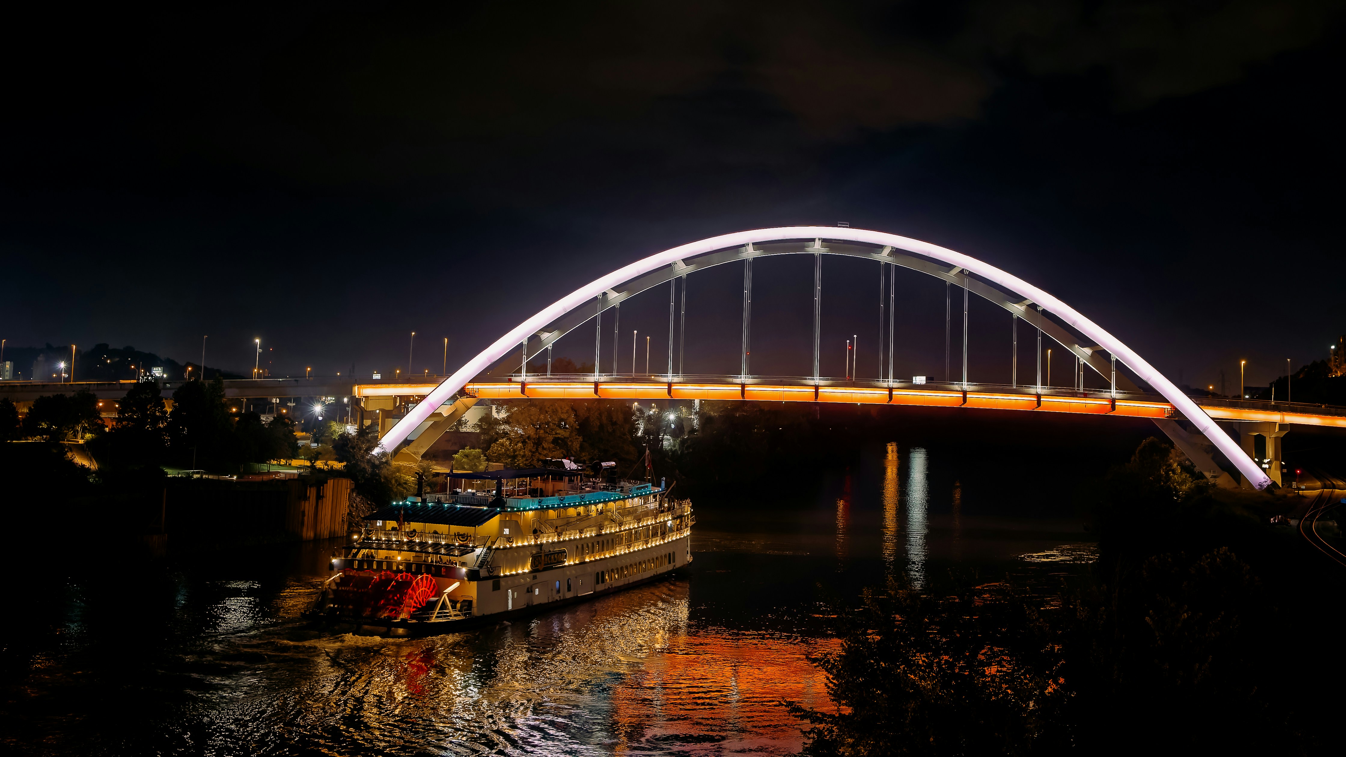 a large boat traveling down a river under a bridge