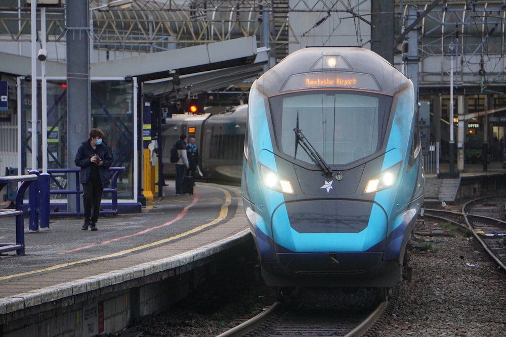 a blue and grey train traveling down train tracks