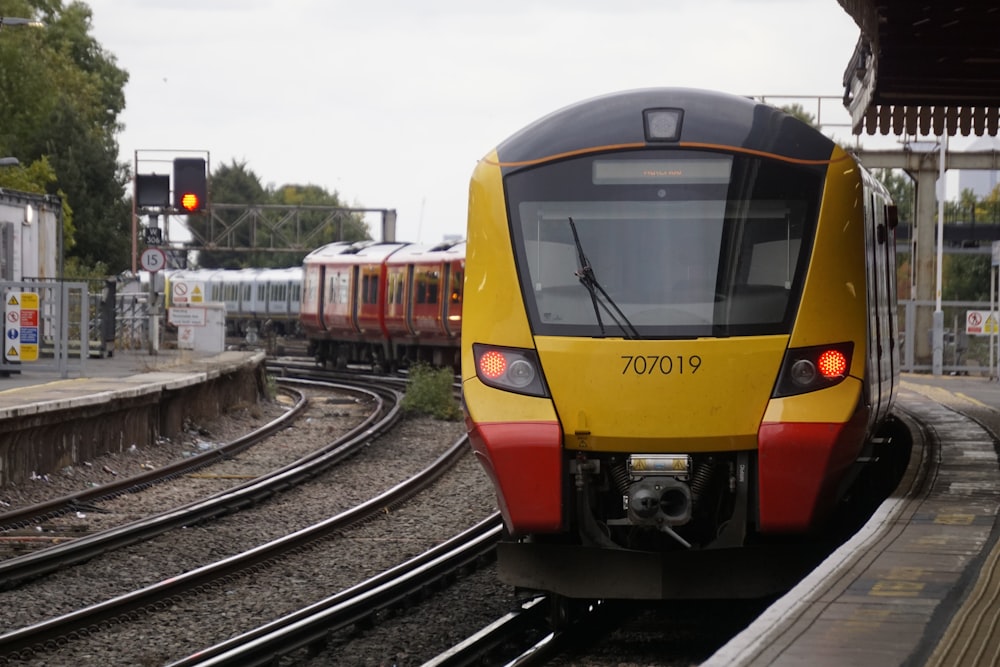 Ein gelb-roter Zug, der die Bahngleise hinunterfährt