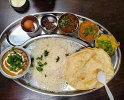 a silver plate topped with rice and different types of food