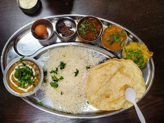 a silver plate topped with rice and different types of food