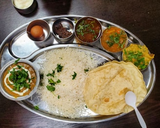 a silver plate topped with rice and different types of food