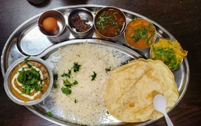 a silver plate topped with rice and different types of food