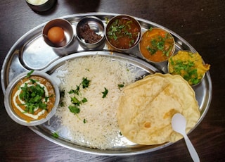 a silver plate topped with rice and different types of food