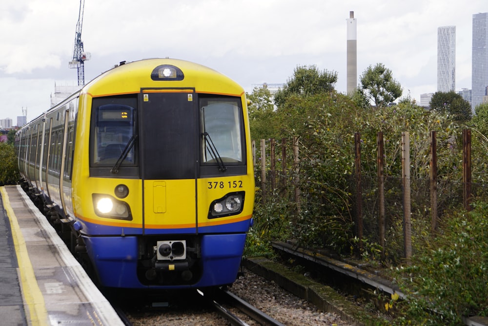 Ein gelb-blauer Zug, der die Bahngleise entlang fährt