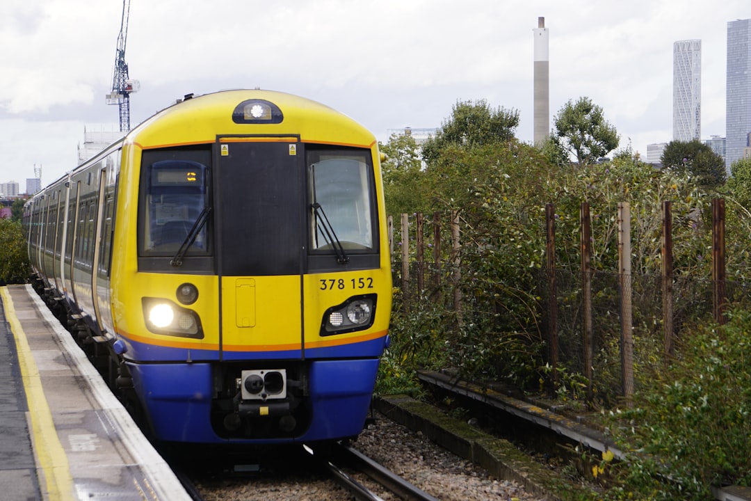 a yellow and blue train traveling down train tracks, A London Underground Class 378