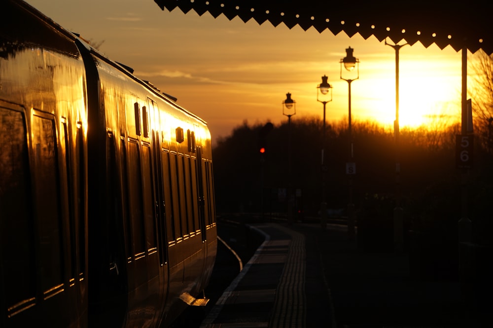 the sun is setting behind a train on the tracks