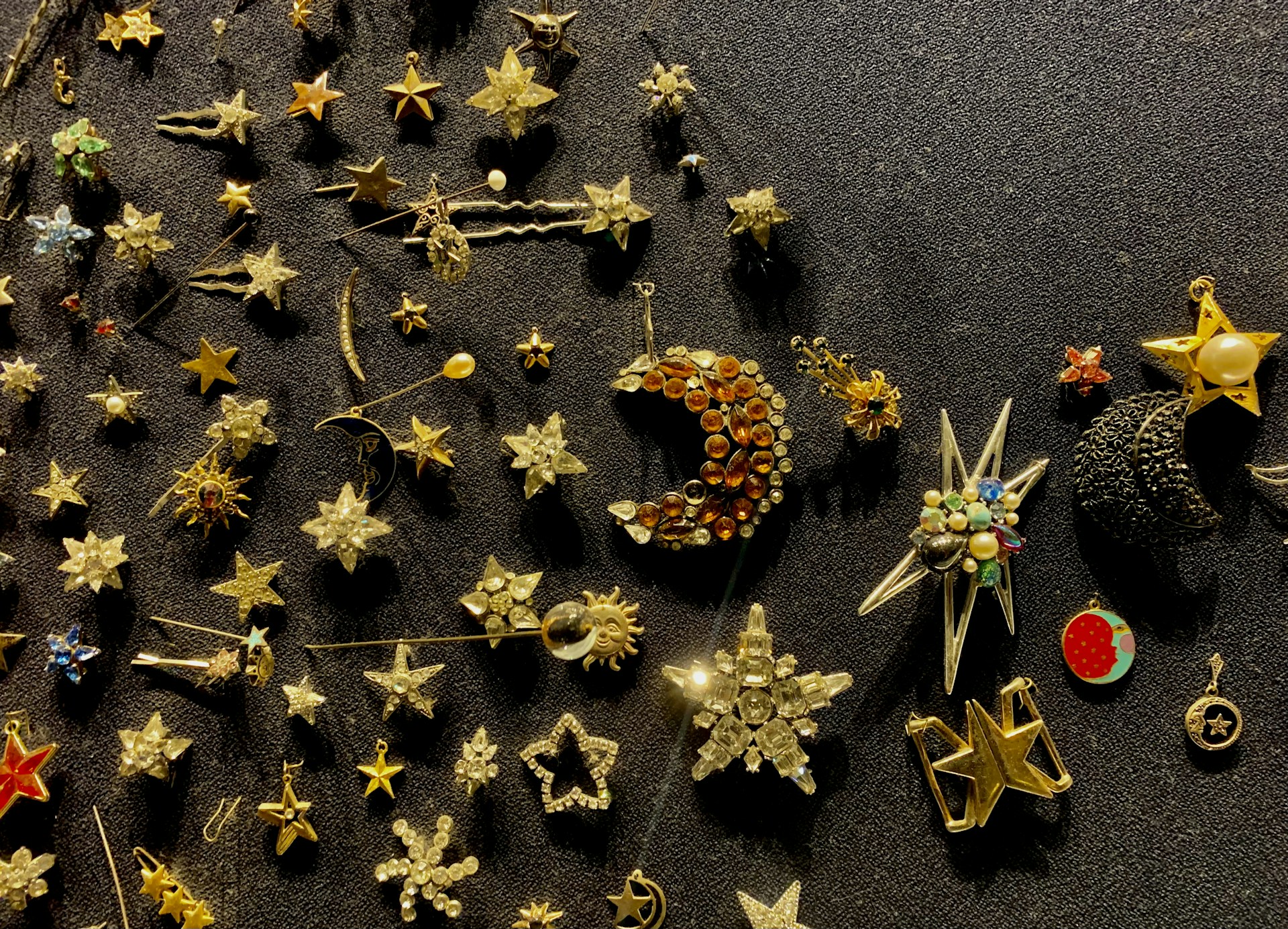 An assortment of hijab accessories including pins and brooches arranged neatly on a wooden table, showcasing their intricate designs and craftsmanship.