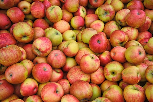 A large pile of red and green apples fills the entire image, with various shades indicating their ripeness. The apples are tightly packed together and appear fresh, with slight variations in color and size.