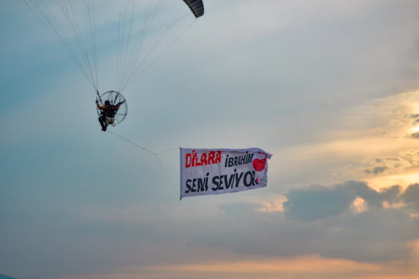 A smiling local family waving up at a paramotor flying overhead, symbolizing unity and shared stories.